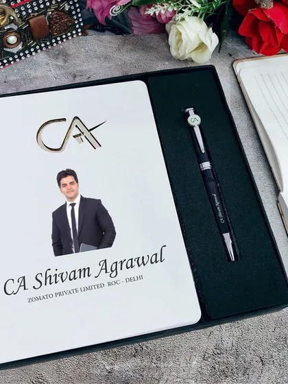 This professional diary and pen set is designed for Chartered Accountants (CAs). The diary features a CA logo, and both items can be personalized with a name and photo.