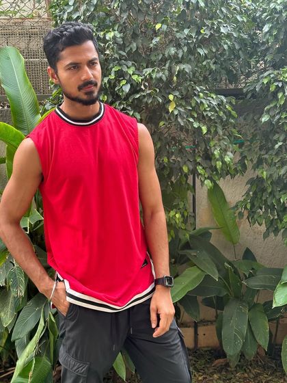 A relaxed and confident pose in a red tank top.