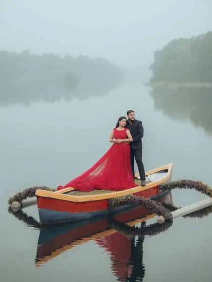 A serene maternity photoshoot on the water. The vibrant red of this trail gown creates a stunning reflection, and the quiet, misty lake setting adds a layer of peacefulness to this beautiful moment.