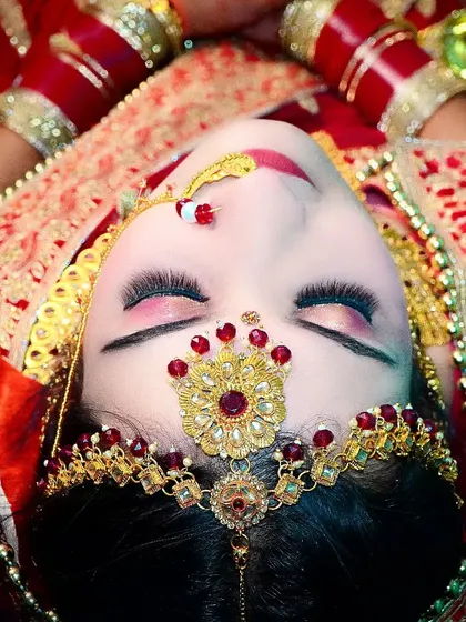 An artistic top-down shot of the bride, focusing on her beautiful eye makeup and the traditional maang tikka. This angle provides a unique and memorable portrait.