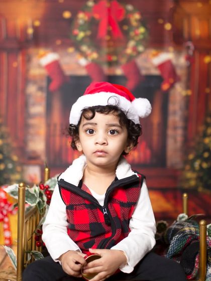 A serious Santa in the making! This toddler looks thoughtful in his festive plaid vest and Santa hat.