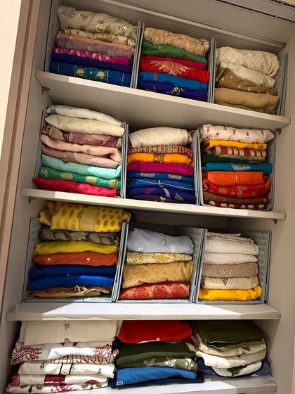 For sarees that are stored folded, we use shelf dividers to create neat, stable stacks. This prevents piles from toppling over and allows you to pull one out without disturbing the rest.