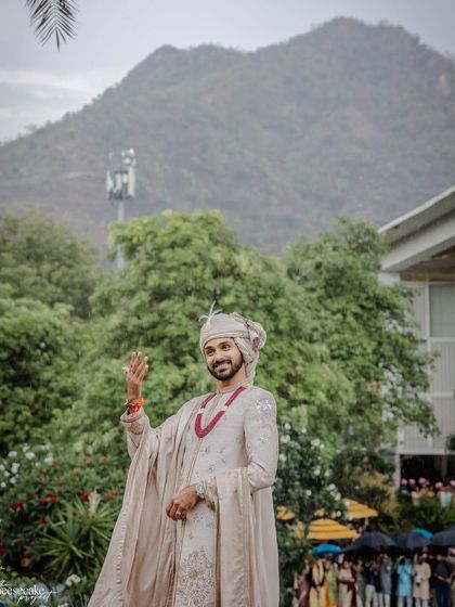 The groom waving happily as he waits for his bride at the mandap.