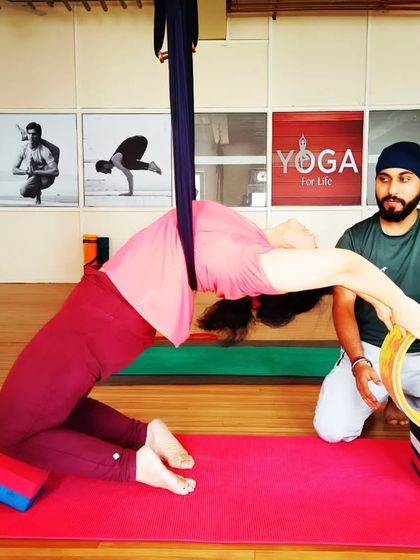 Guiding a student through a supported camel pose with a yoga wheel. The wheel follows the curve of the spine, allowing for a safe and deep release.