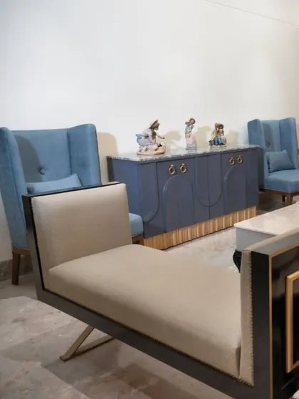 This seating arrangement features custom-designed furniture, including light blue high-back lounge chairs that add a pop of color. The scene is anchored by a stylish dark blue console with brass ring pulls, showcasing our ability to create unique, bespoke pieces.