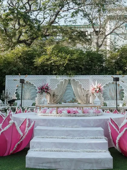 An identical shot of the Lotus Mandap, emphasizing the clean lines and beautiful symmetry of the design. The vibrant pink lotuses provide a beautiful pop of color against the white stage.