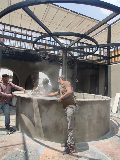 The raw construction phase of the circular bar, showing the metal framework and concrete work that forms the foundation of the final design.