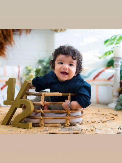 A joyful baby enjoying his half-birthday session. His happy expression and the rustic decor create a warm and inviting portrait.