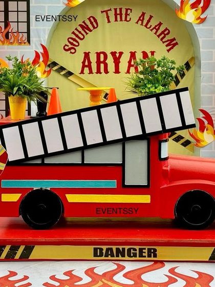 A close-up of the firetruck prop and the firefighter cutout. The attention to detail, including the "Danger" sign and traffic cones, makes the theme more interactive and fun for kids.