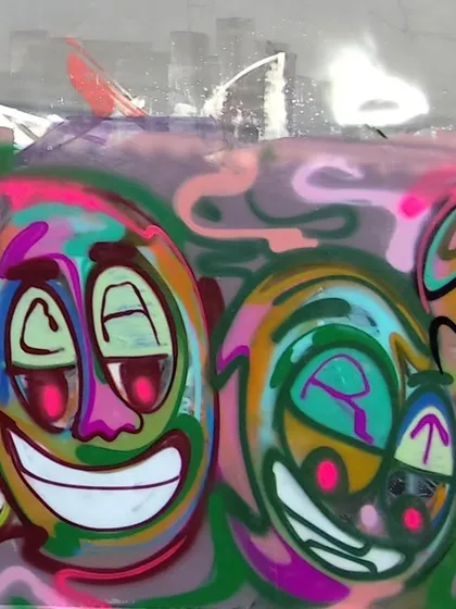 A close-up of the smiling faces from the long wall. Each one has a slightly different expression and color combination, adding to the playful, hallucinatory vibe.