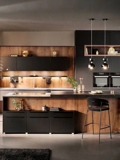 This elegant kitchen combines black matt lacquered fronts with warm wood panels and open shelves. A backlit recess rail adds a cozy glow for intimate gatherings.