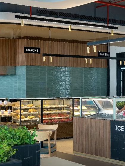 The sweets and snacks counter at Haldiram's uses warm wood paneling and a tiled backsplash to create a clean and inviting display. The design honors the brand's 80-year tradition while embracing a modern aesthetic.