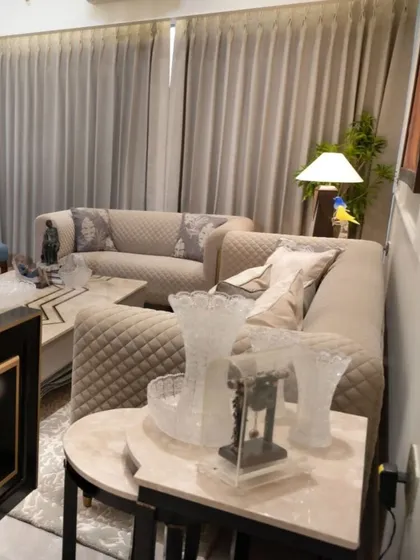 In this living room, we used quilted beige sofas to create a cozy and luxurious feel. The space is accessorized with elegant glass vases and an hourglass, reflecting the client's sophisticated taste while maintaining a comfortable, lived-in atmosphere.