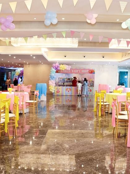 A wide view of the party hall, showing the colorful table settings and festive bunting hanging from the ceiling.