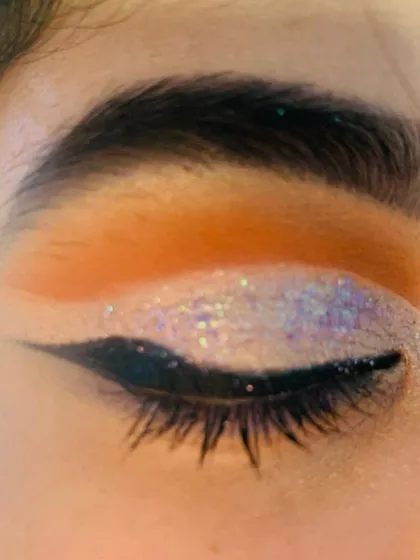 A close-up of a full cut crease eye makeup look, showing the sharp definition and glitter application.