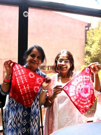 Two participants proudly showing off the beautiful red napkins they created. The patterns are so different, yet both were made using the same dye bath and techniques.