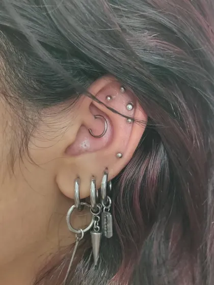 A fully styled ear project featuring a daith, multiple helix piercings, and decorated lobes. We can help you achieve a similar curated look over time.