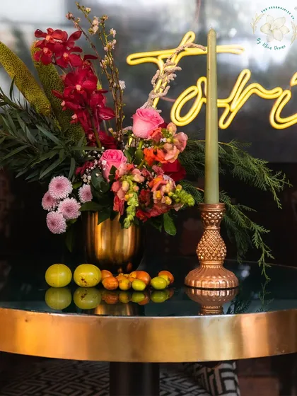 A vibrant floral centerpiece with a mix of textures and colors, set against a neon sign. This demonstrates our ability to blend classic floral design with modern, edgy elements.