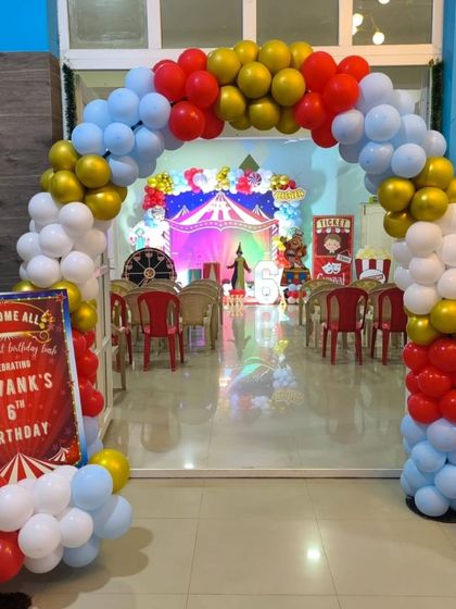 The grand entrance to the carnival party, with a red, white, blue, and gold balloon arch and a personalized welcome sign.