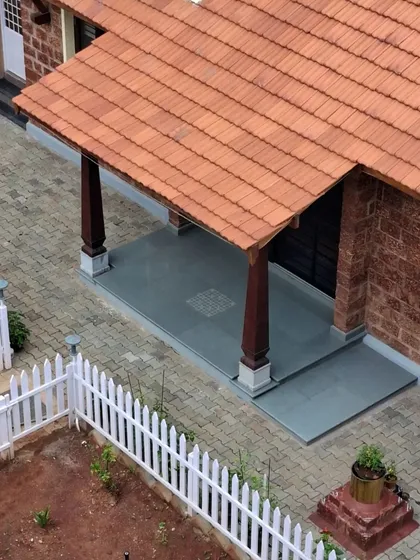 The front sit-out of the Basavanagudi house is a perfect spot to enjoy the morning sun or play a game of 'Chaukabara'. The space is defined by traditional wooden pillars and a cool stone floor, inviting connection with the outdoors.