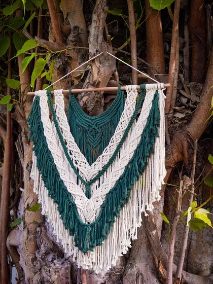 This foresty boho wall hanging combines deep green and natural off-white for a calming, nature-inspired look. The V-shape design and layered textures make it a beautiful and serene addition to any room.