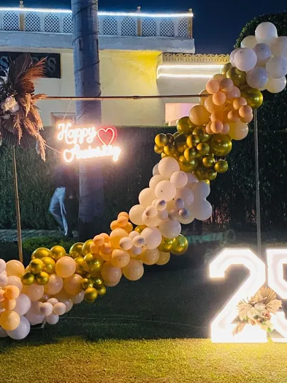 This shot shows the anniversary setup at dusk, with the neon sign and marquee number glowing beautifully in the garden setting.