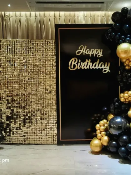 A classic and elegant black and gold birthday backdrop. This design combines a gold sequin panel with a solid black panel, framed by a black and gold balloon arrangement.