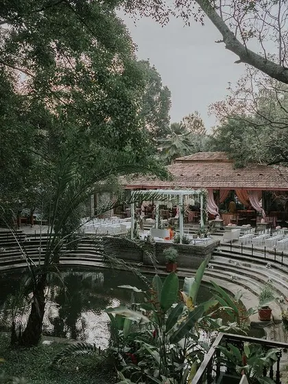 A high-angle view of the Pond Pavilion set for a wedding, showing the amphitheater-style seating and the beautiful waterside mandap.