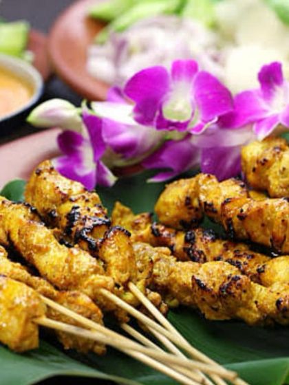 Classic Chicken Satay skewers, grilled and served on a banana leaf. This dish is accompanied by a rich peanut sauce, offering an authentic taste of Southeast Asia.