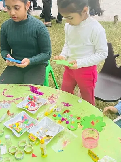 Art is a wonderful activity for all ages. Here, older and younger children work side-by-side at a craft table, sharing materials and ideas in a collaborative and creative environment.