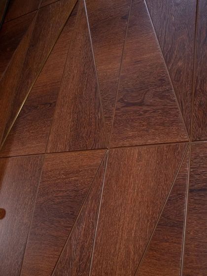 A detail shot of the geometric pattern and metal trims on the Sucupira veneer door, highlighting the open grain finish.