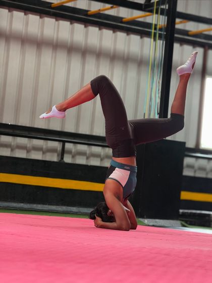 An adult student holds a beautiful scorpion headstand, demonstrating incredible flexibility and balance.