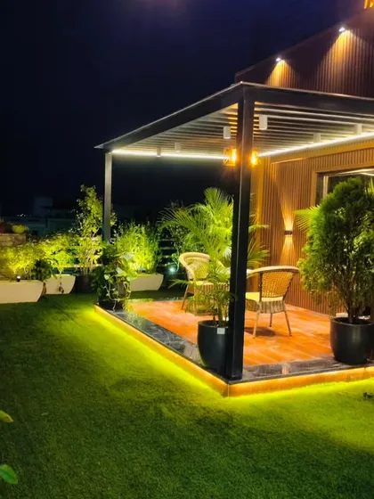 The pergola and swing chair area at night, surrounded by illuminated planters, creating a perfect spot for quiet evenings.