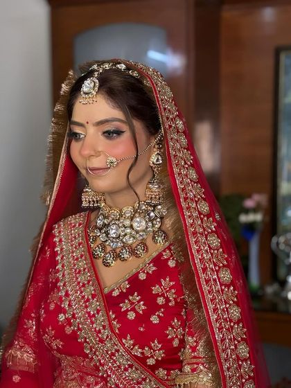 A candid moment capturing her bridal glow. The soft hairstyle with a matha patti complements the heavy neckpiece and radiant makeup.