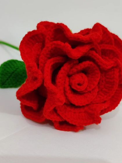 A clean, simple shot of the single red crochet rose against a white background.