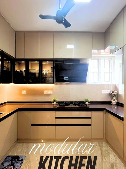 A real-life view of a modular kitchen with beige high-gloss cabinets and a dark countertop. The design is clean, functional, and perfect for daily use.