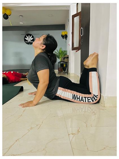 A student in my teacher's training course practices a wall-assisted variation of Poorna Bhujangasana, the full Cobra Pose, to safely deepen her backbend.