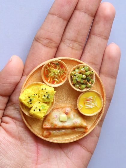 A Kathiawadi thali held in my hand, showcasing its tiny size and intricate details.