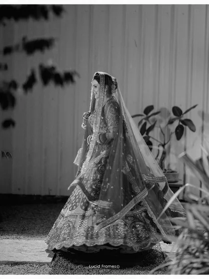 A timeless side profile of the bride in her magnificent lehenga, the black and white tones emphasizing the texture and detail.