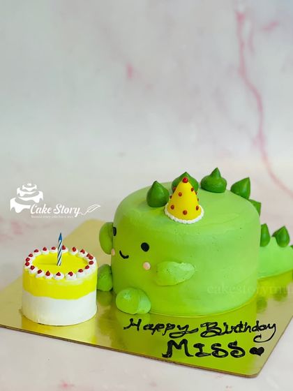 A cute, minimalist dinosaur-shaped cake. This simple green cake is perfect for a small celebration and comes with its own tiny birthday cake.