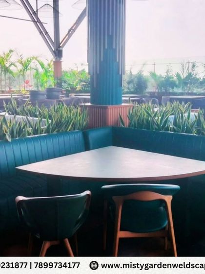 The corner booth seating is surrounded by a bed of hardy snake plants, a low maintenance choice that adds a touch of green to the interior landscaping.