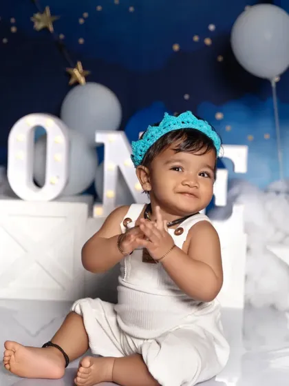 A joyful portrait celebrating the first birthday. The lit-up 'ONE' sign and starry night theme create a magical setting for this milestone moment.