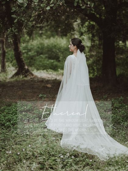 An ethereal portrait of the bride in a forest setting, her long veil catching the light beautifully.