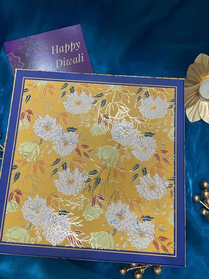 The lid of our stunning yellow and blue floral gift box. The intricate design and gold foil accents make the unboxing experience feel extra special.