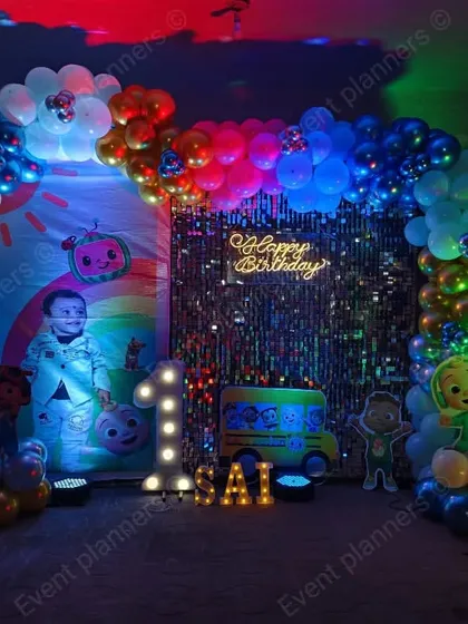 A Cocomelon-themed first birthday with a shimmering backdrop and colorful lights.