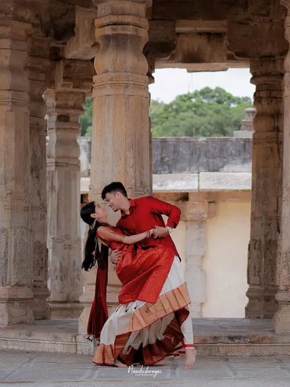 A graceful dance dip between the couple, framed by the timeless stone pillars of the temple.