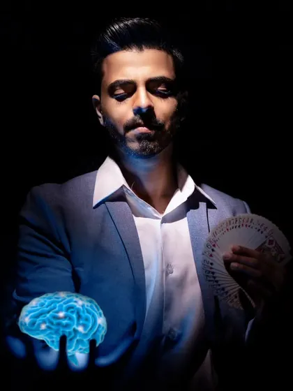 A dramatic shot of me holding a fan of cards in one hand and a glowing brain in the other. This represents my work in mentalism, unlocking the power of the mind.