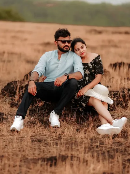 A relaxed and happy couple sitting together in a field, a beautiful and natural pre-wedding portrait.