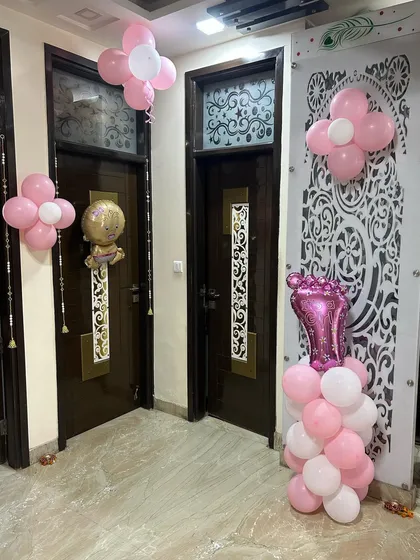 Simple and sweet balloon decorations for a baby girl's arrival. This image shows small balloon clusters and foil shapes placed strategically around the home's doorways and corners to create a festive atmosphere.