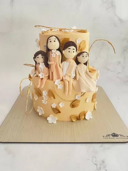 A personalized family cake. This two-tiered cake is decorated with custom fondant figures representing the members of a family, surrounded by golden leaves.
